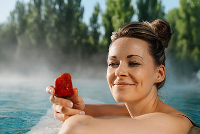 Frau im Wasser der Spreewald Therme hält eine rote Erdbeere in der Hand