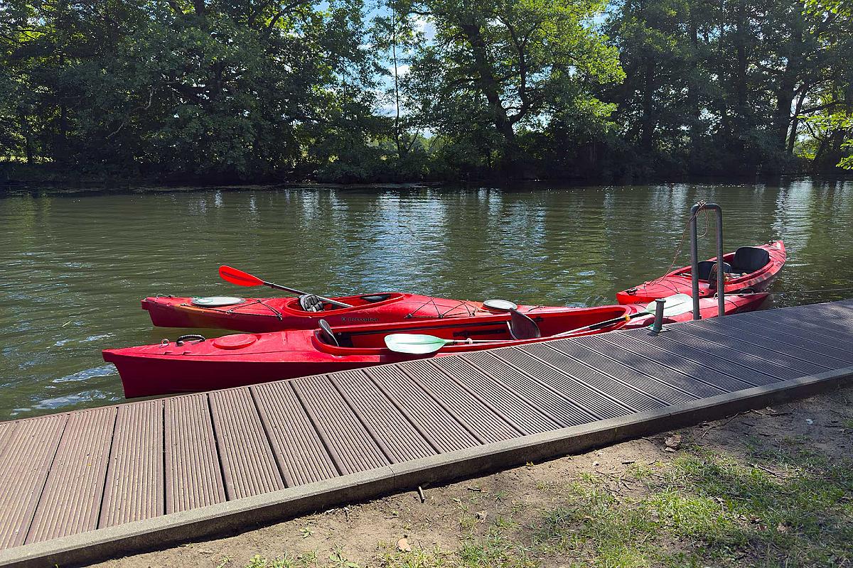 Gasthaus Lehnigksberg - Zwei rote Kajaks liegen im Wasser, festgezurrt am Steg.