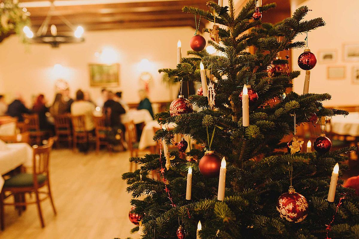 Gasthaus Lehnigksberg - Weihnachtsbaum mit Kerzen im Gasthaus, im Hintergrund eine Feier